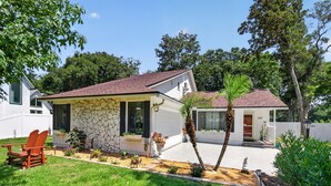 A single-story house with a stone facade, a red roof, and a well-maintained lawn. - Backyard Oazis (St. Augustine)