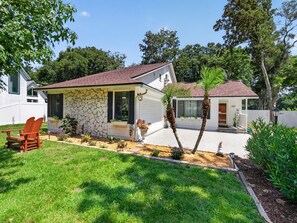 A single-story house with a stone facade, a red roof, and a well-maintained lawn. - Backyard Oazis (St. Augustine)