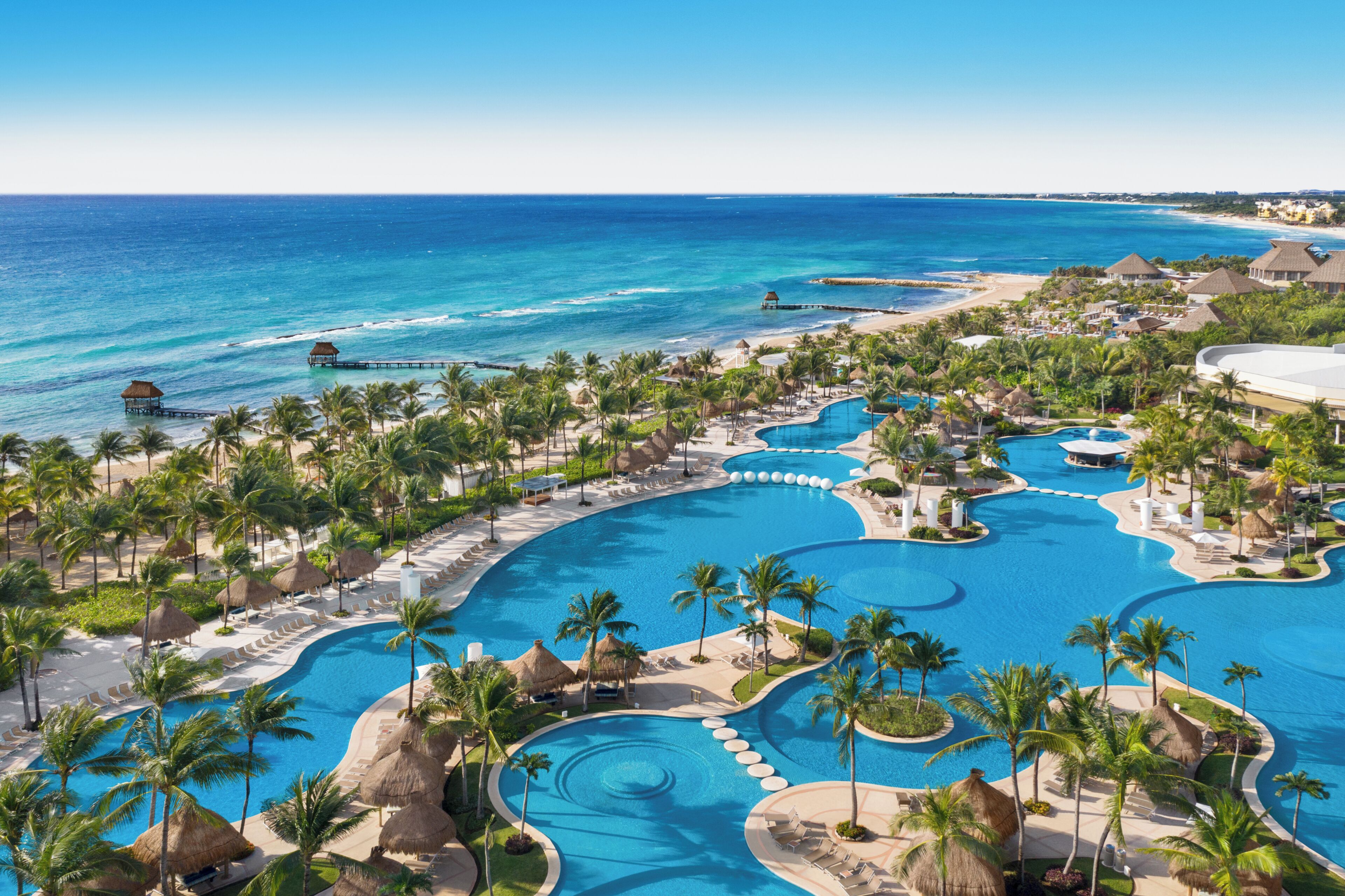 A resort with multiple swimming pools, palm trees, and a beach.