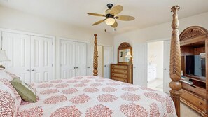 Ein Schlafzimmer mit einem Himmelbett, einem Deckenventilator, einem Schminktisch und einem Fernseher.