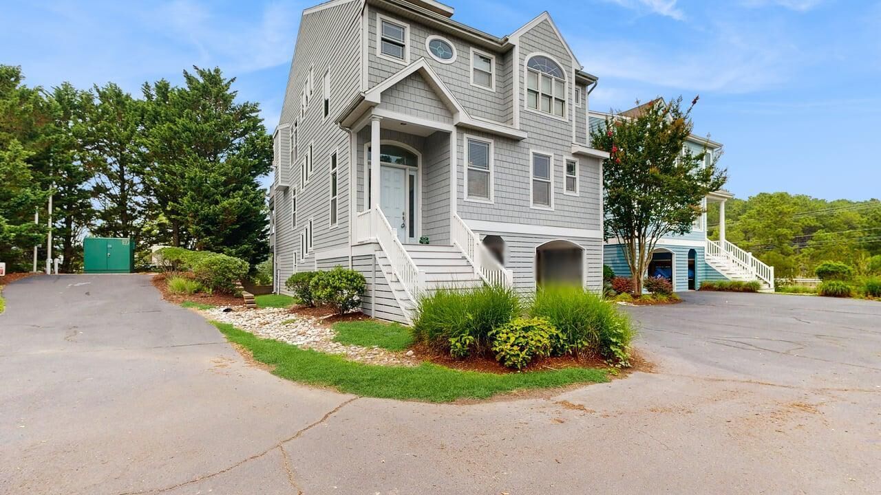 A two-story house with a front porch, a driveway, and a green lawn.