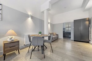 A modern kitchen with a built-in refrigerator, a dining area with a round table and chairs, and a sofa in the background. - The City Retreat (London)