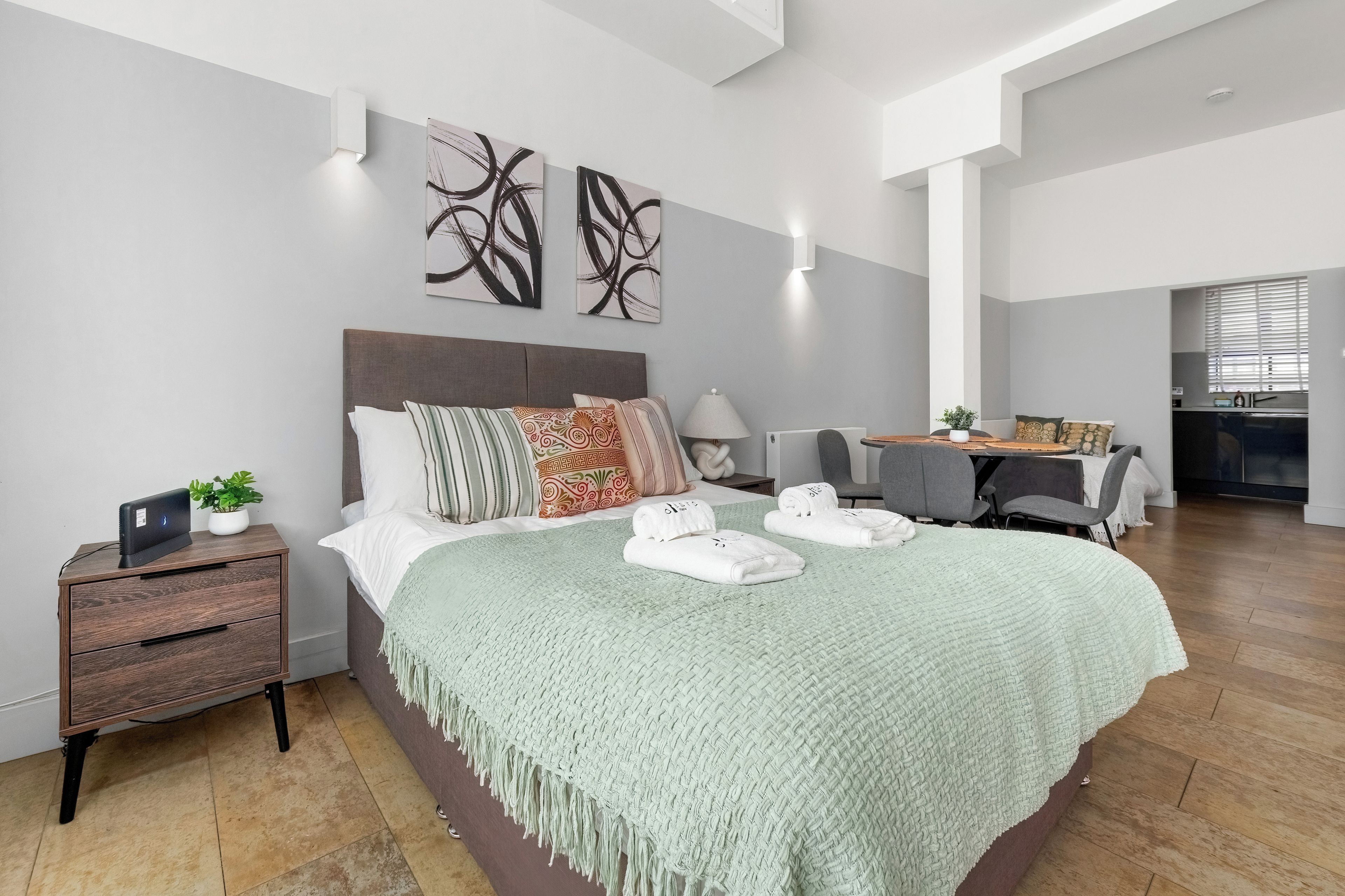 A modern bedroom with a large bed, bedside tables, a desk, and a chair.