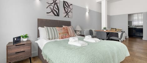 A modern bedroom with a large bed, bedside tables, a desk, and a chair.