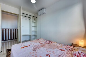 A bedroom with a bed, a wardrobe, and an air conditioning unit. - Vétyvers - Climatisation - Terrasse (Saint-Louis)