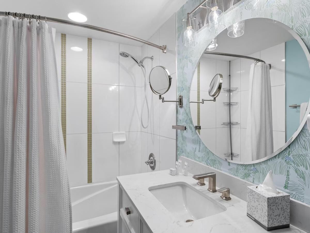 A modern bathroom with a shower, a large mirror, and a vanity with a sink.