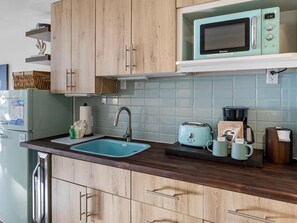 A kitchen with wooden cabinets, a blue sink, a microwave, a toaster, and a coffee maker.