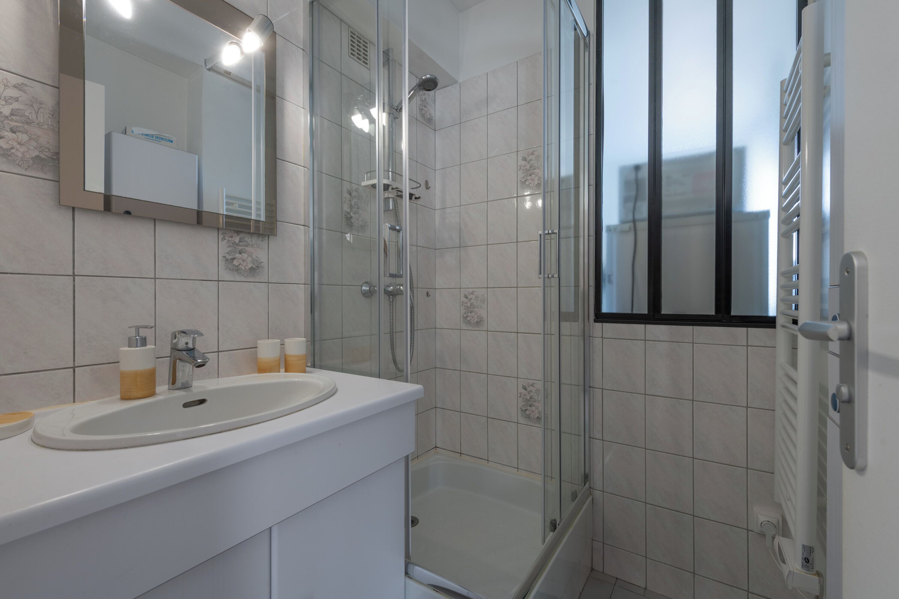 Ein modernes Badezimmer mit Duschkabine aus Glas, einem weißen Waschbecken und einem großen Spiegel.