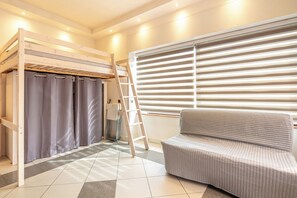 A room with a bunk bed, a sofa, a ladder, and a window with blinds. - Le Local - Climatisation - Petfriendly (Saint-Martin-d'Hères)