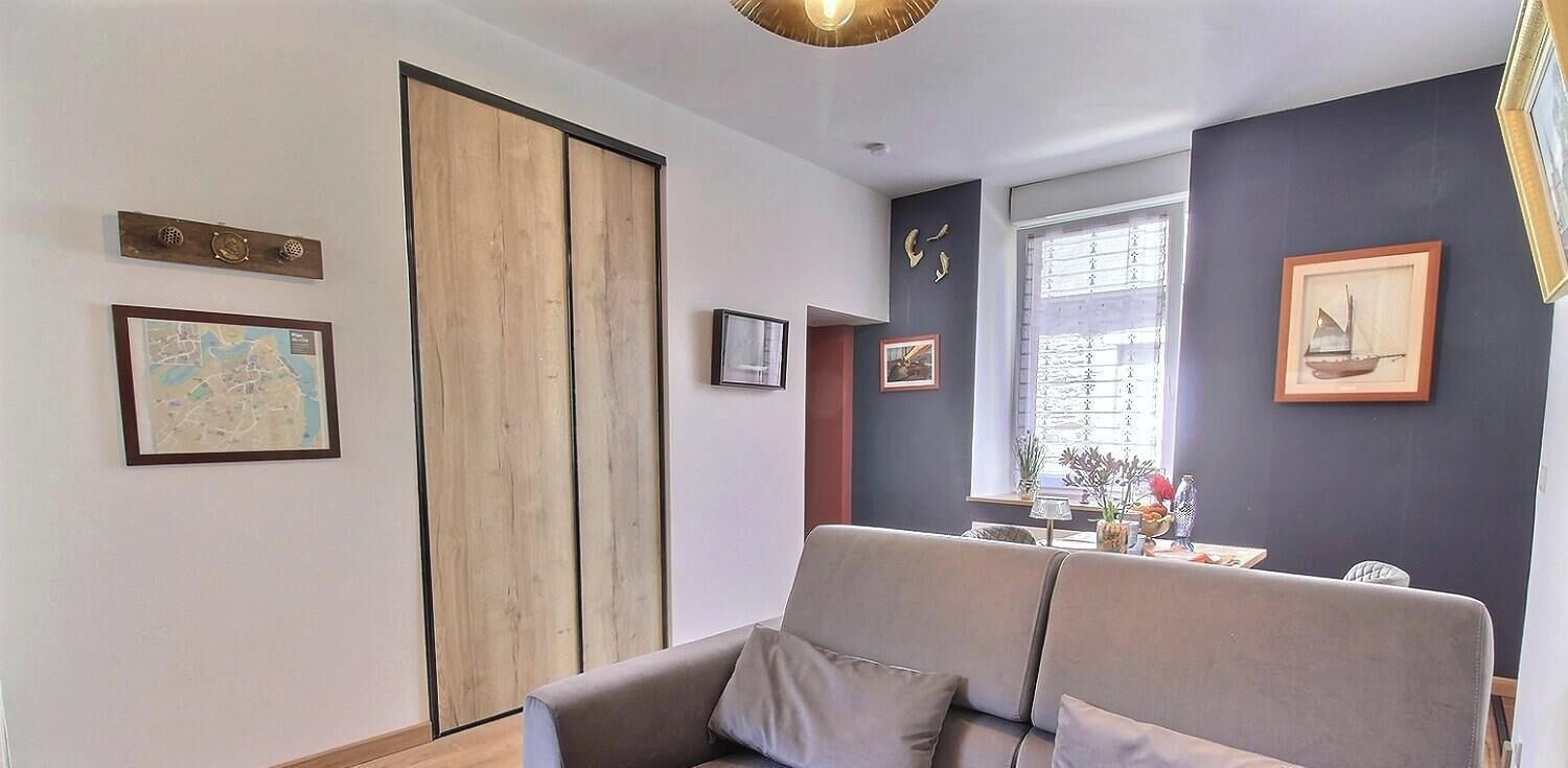 A living room with a sofa, a wooden door, and framed pictures on the walls.