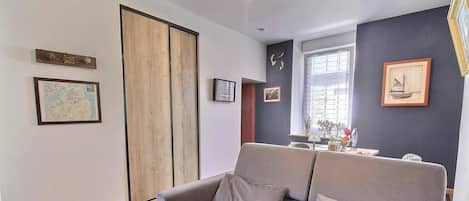 A living room with a sofa, a wooden door, and framed pictures on the walls.