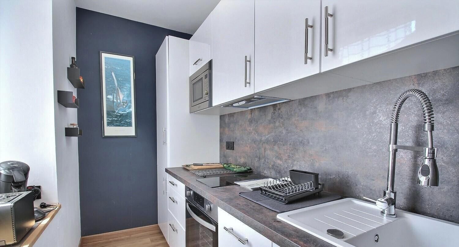 A modern kitchen with white cabinets, a stainless steel sink, and a microwave.