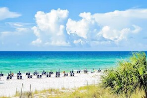 Ein Strand mit Liegestühlen und blauem Himmel.