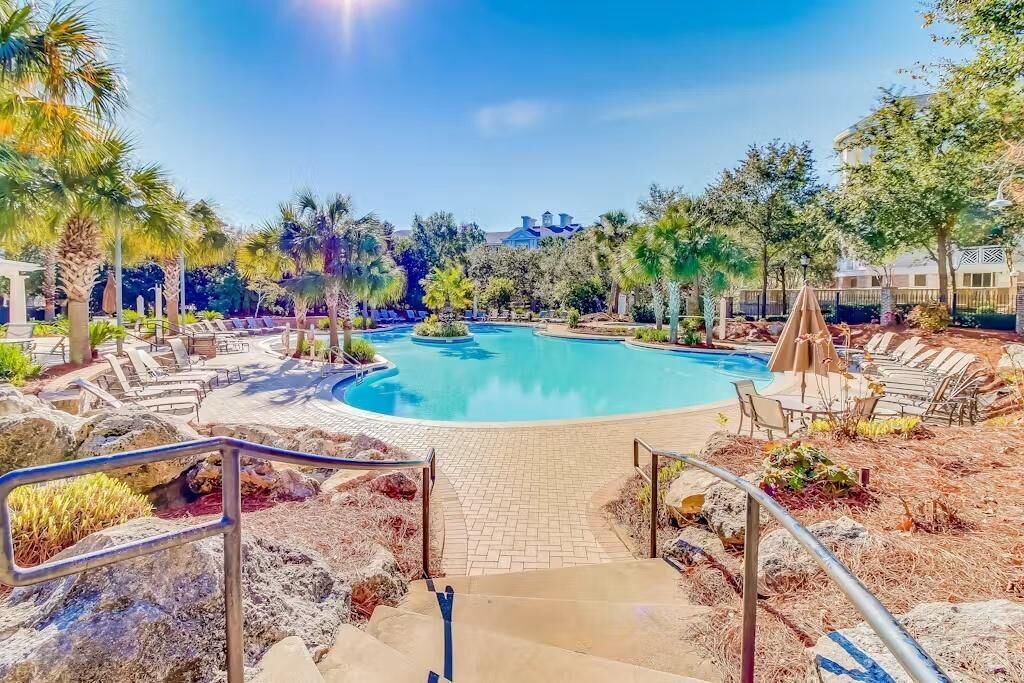 A pool area with lounge chairs and a clear sky.