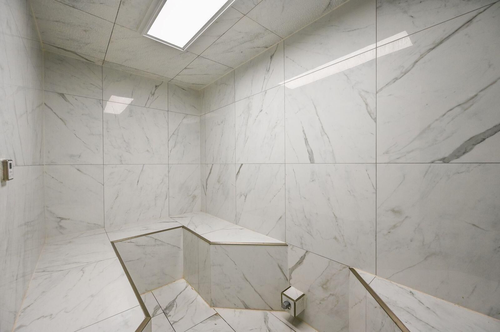 Un baño moderno con paredes de mármol y un tragaluz.