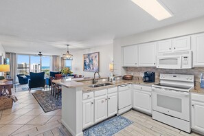 A modern kitchen with white cabinetry, a built-in microwave, and a coffee maker. - Pelican Beach Terrace 903 (Destin)