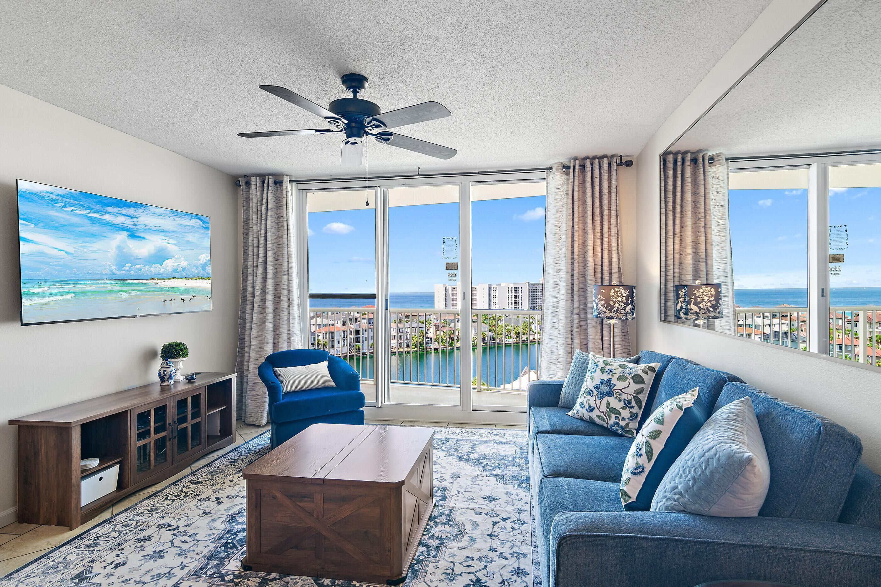 Ein Wohnzimmer mit großem Fenster, Deckenventilator und Blick auf die Stadt.