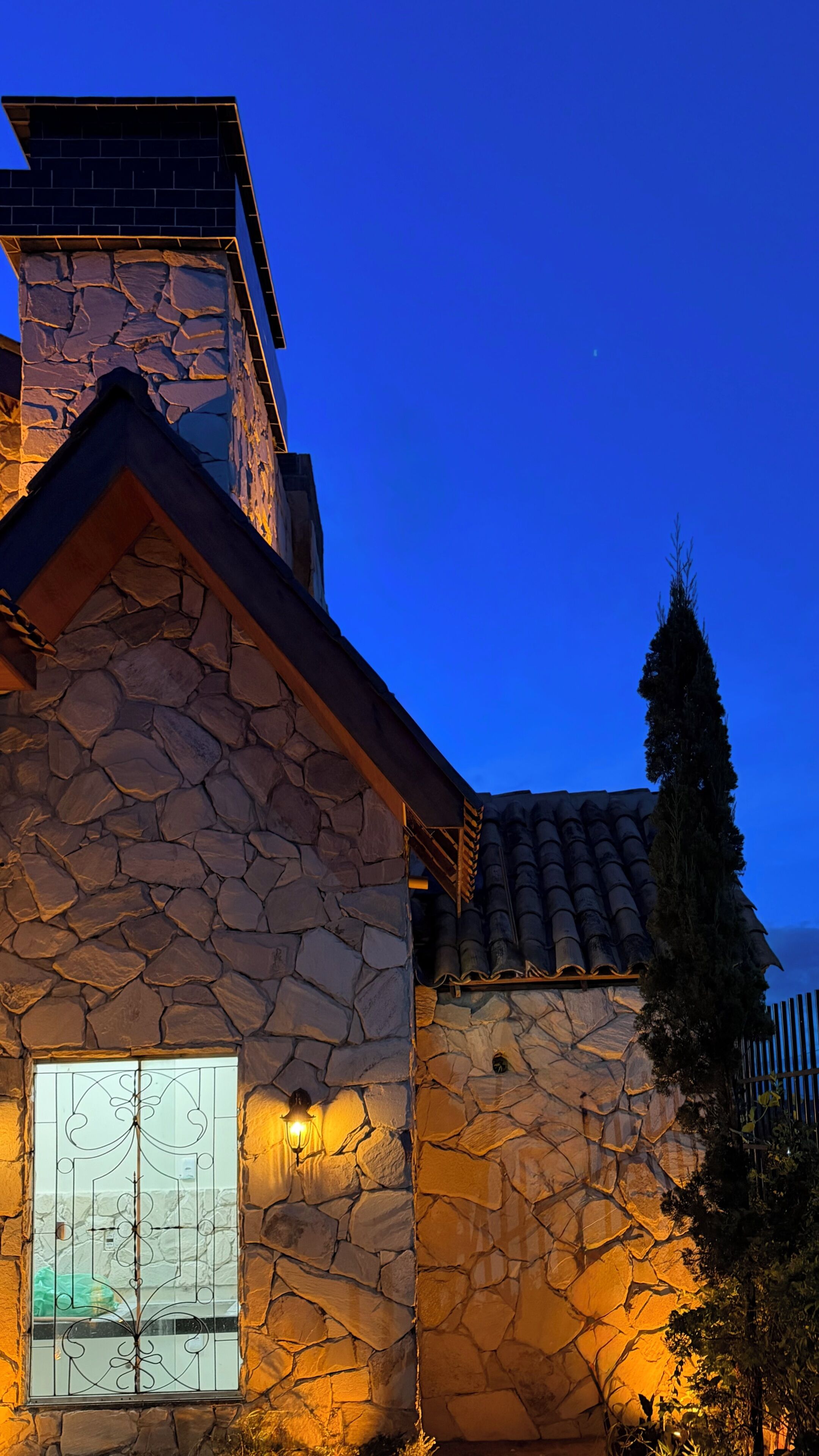 A stone building with a large window and a metal gate.