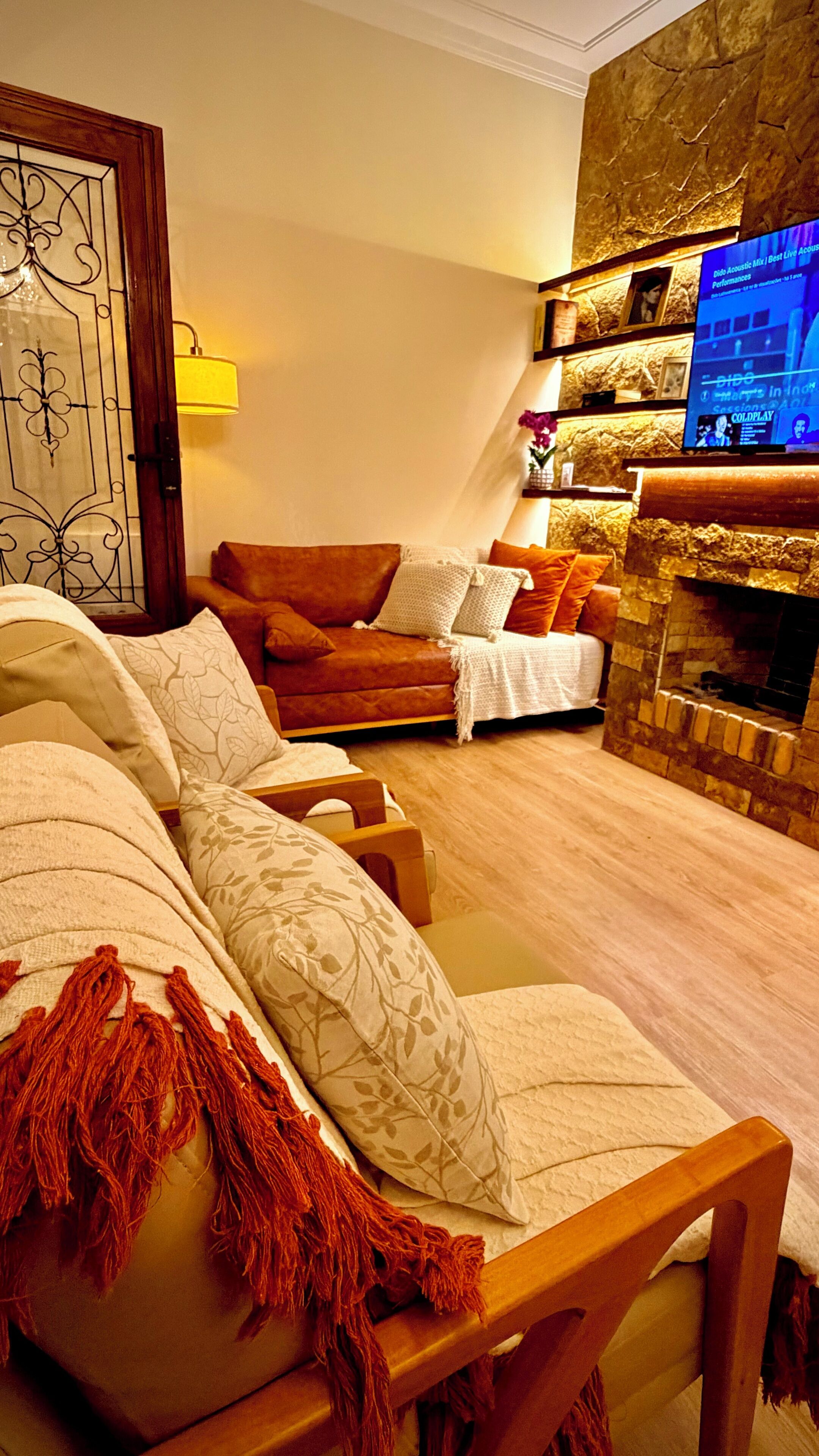 Una sala de estar con un sofá, una mesa de centro de madera, una chimenea y un televisor montado en la pared.
