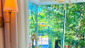 A dining area with a glass table, chairs, a potted orchid, and a chandelier. - Chalé Jardim Itália (Tiangua)