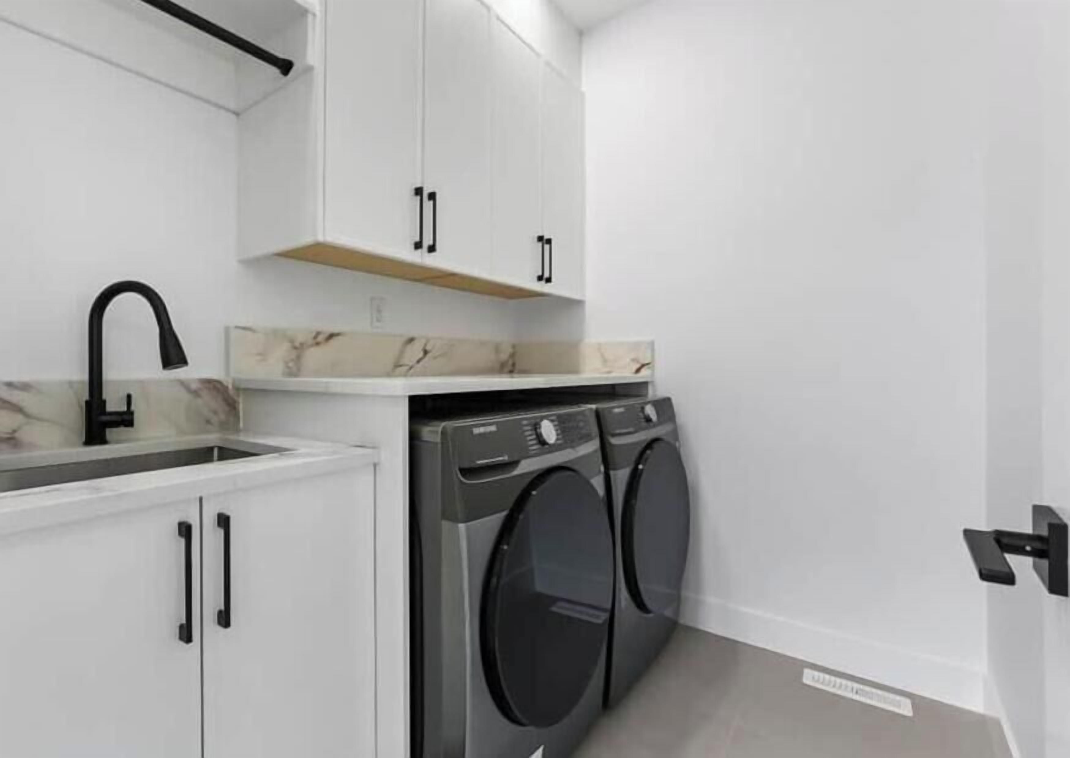 Ein kleiner Waschraum mit Waschmaschine, Spüle und Schrank.