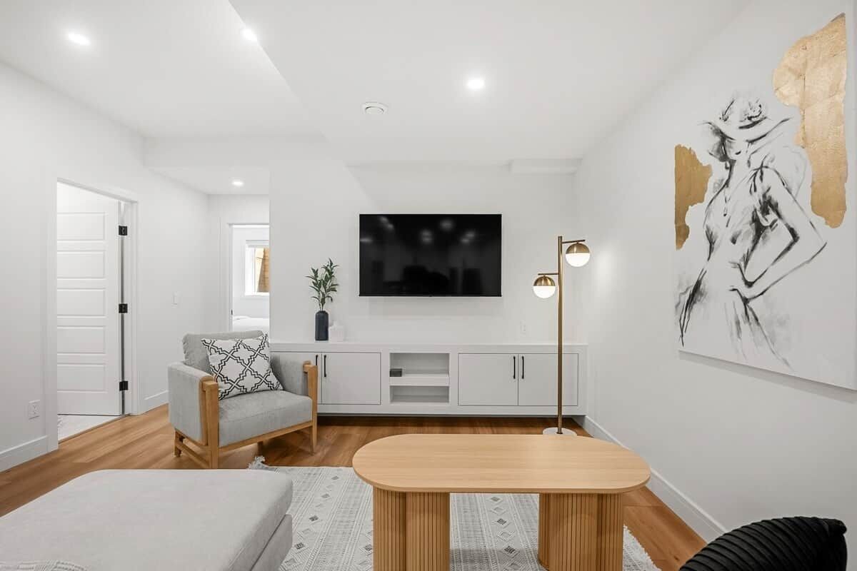 A modern living room with a flat-screen TV, a sofa, a coffee table, and a painting on the wall.