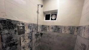 Un baño con ducha, inodoro y una ventana pequeña.