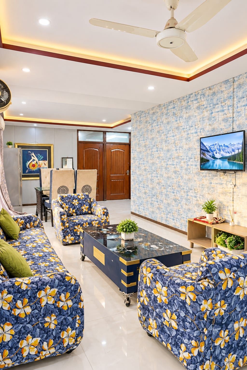 A living room with a sofa set, a coffee table, a television, and a ceiling fan.