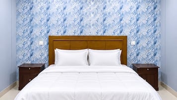 Quarto com cama, mesas de cabeceira, ventilador de teto e ar condicionado.