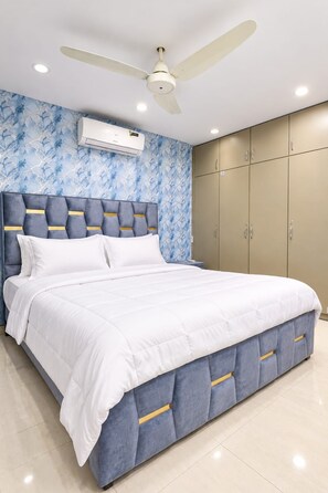 A bedroom with a bed, a ceiling fan, and a wardrobe.