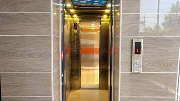 An elevator with a digital display showing the number 1, a control panel, and a ceiling with a blue sky and clouds design.
