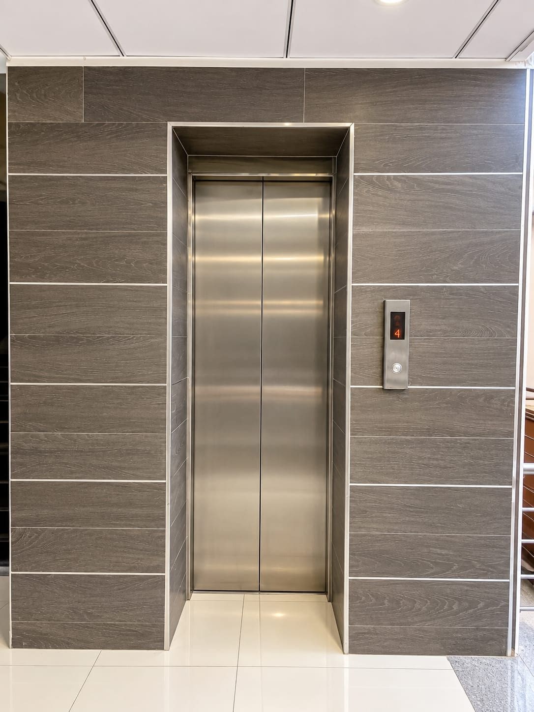 Um elevador moderno com acabamento metálico e um visor digital exibindo o número 4.