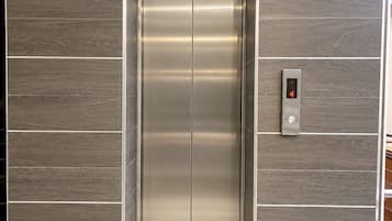 Um elevador moderno com acabamento metálico e um visor digital exibindo o número 4.