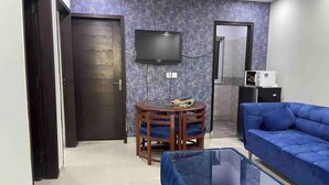 Una sala de estar con un sofá, una mesa de centro, un televisor y una puerta.