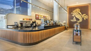 Ein modernes Café-Interieur mit einer gebogenen Theke, Espressomaschinen und einer Auswahl an Getränken.
