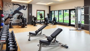 Ein Fitnessstudio mit Kraftgeräten, Cardiogeräten und einem Wandgemälde eines Läufers.