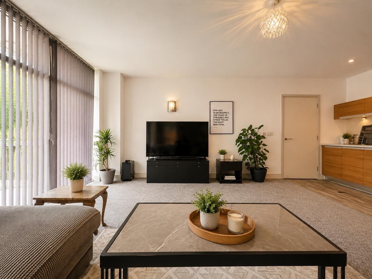 A modern living room with a flat-screen TV, a coffee table with plants, and a minimalist design.