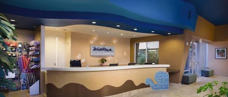 A reception area with a curved counter, a sign reading "Wyndham," and a plant on the counter.