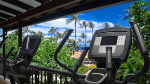 Exercise equipment with a digital display, set against a backdrop of lush greenery and a clear blue sky. - Ocean Front Studio at Marriott's Maui Ocean Club on Kaʻanapali Beach (Lahaina)