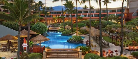 A resort with a central pool, palm trees, and a building with multiple floors.