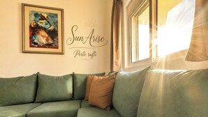 Ein grünes Sofa mit einem Kissen, ein gerahmtes Bild und eine Wandtafel mit der Aufschrift 'Sun Arise Porto ratti'.