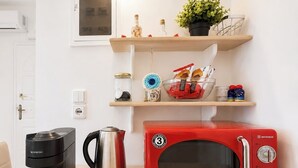 Eine Küchenzeile mit einer roten Mikrowelle, einer schwarzen Espressomaschine und einem Edelstahl-Wasserkocher auf einer Holz Arbeitsplatte.