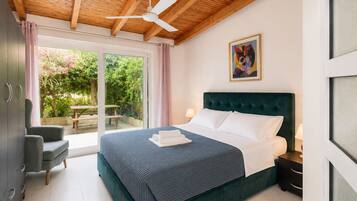 Une chambre à coucher avec un lit, un bureau et une chaise. Il y a une fenêtre avec des rideaux et une vue sur la verdure à l’extérieur.