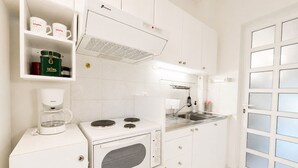 Eine moderne Küche mit weißen Schränken, einem eingebauten Backofen, einer Kaffeemaschine und einem Fenster mit Milchglas.