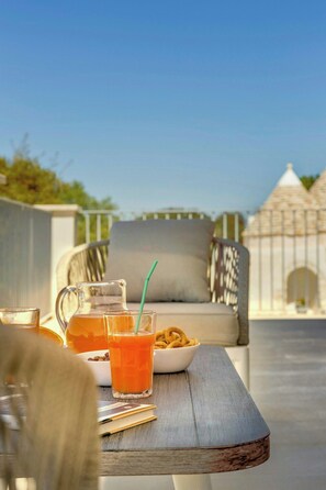A table with a pitcher, a glass with a straw, and a bowl of snacks. - Valle d'Itria villa with saltwater and bubble pool (Ostuni)