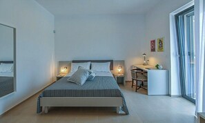 Un dormitorio moderno con cama, mesitas de noche, un escritorio y una silla.