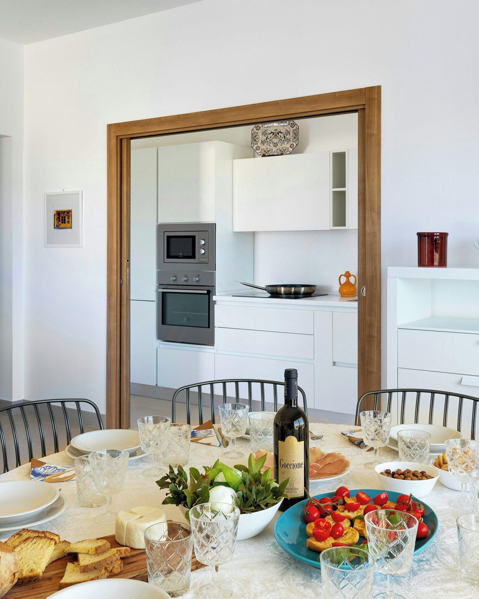 Une table à manger dressée avec des assiettes, des verres, une bouteille de vin et de la nourriture.