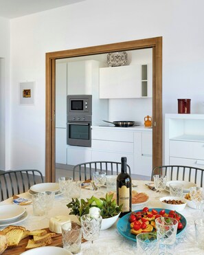 A dining table set with plates, glasses, a bottle of wine, and food. - Valle d'Itria villa with saltwater and bubble pool (Ostuni)