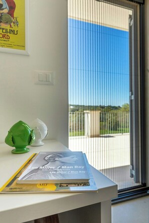 Une pièce comprenant un bureau, un livre intitulé « Lee Miller / Man Ray », et une fenêtre donnant sur une clôture et de la verdure.