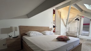 A bedroom with a wooden bed, white bedding, a nightstand with a lamp, and a skylight above. - VILLA NORA: HOUSE WITH A SWIMMING POOL IN DEMANGE-AUX-EAUX (DEMANGE BAUDIGNECOURT)